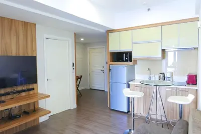 a kitchen with white cabinets and a table and chairs at Modern 1BD in Ortigas, WiFi ,Netflix ,Pool ,Gym in Manila