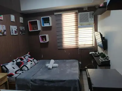 a bedroom with a bed and a window and a table at pierrecondotel in Manila