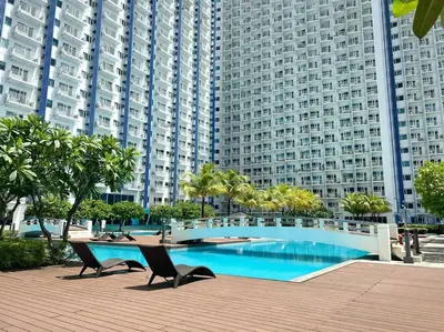 a swimming pool with two chairs and a large building at Belle 4621 by TPS in Manila