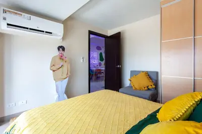 a man standing in a bedroom with a bed at Korea In The City Staycation with Pool, Gym and More in Manila