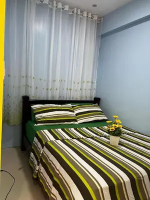 a bedroom with a bed with yellow and green stripes at vevilyn condotel in Manila
