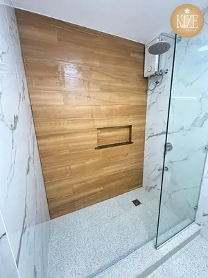 a shower in a bathroom with a wooden wall at Kize Staycation in Manila