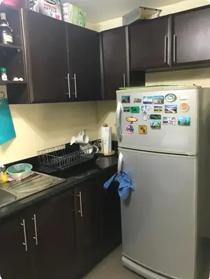 a kitchen with a white refrigerator with magnets on it at Montecito unit near airport in Manila