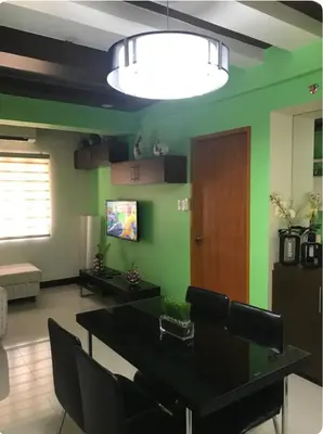 a living room with a table and a green wall at Montecito unit near airport in Manila