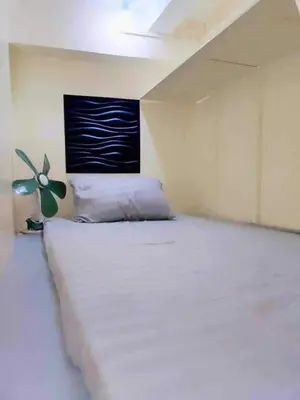 a bedroom with a white bed with a painting on the wall at RDC- Baclaran Transient Capsule in Manila