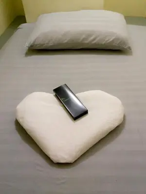 a cell phone sitting on a heart shaped pillow on a bed at RDC- Baclaran Transient Capsule in Manila