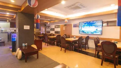 a restaurant with tables and chairs and a large screen at RedDoorz Premium at JjimJBang Hotel Spa in Manila