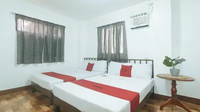 two beds in a room with white walls and windows at RedDoorz at Joels Apartelle in Calaboso