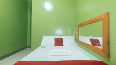 a small bedroom with a bed with a mirror at RedDoorz at Joels Apartelle in Calaboso