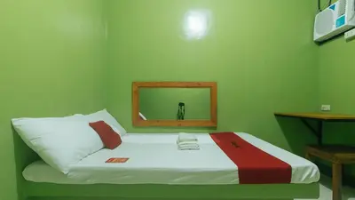 a green room with a bed with a mirror at RedDoorz at Joels Apartelle in Calaboso