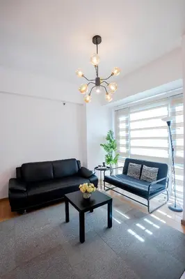 a living room with a black couch and a table at Premium 1BR unit at The Avant in Manila
