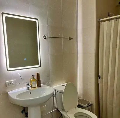 a bathroom with a toilet and a sink and a mirror at Charming 3-BR Condo in BGC in Manila