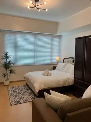 a bedroom with a bed and a couch and a window at Contemporary Studio at Avant BGC in Manila