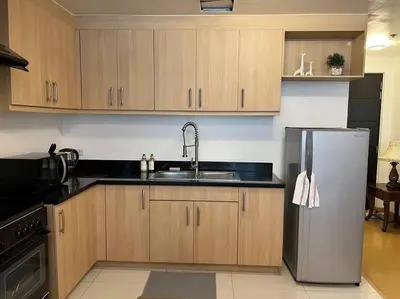 a kitchen with wooden cabinets and a stainless steel refrigerator at Contemporary Studio at Avant BGC in Manila