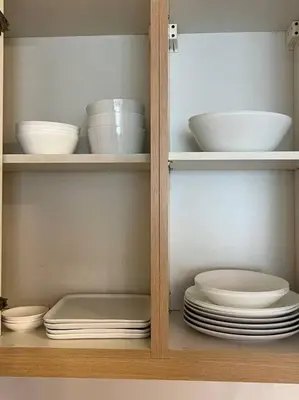 a cabinet filled with white bowls and plates and bowls at Contemporary Studio at Avant BGC in Manila