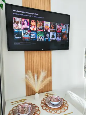 a tv on a wall with a table with food at Paradise Realm Condotel in Manila