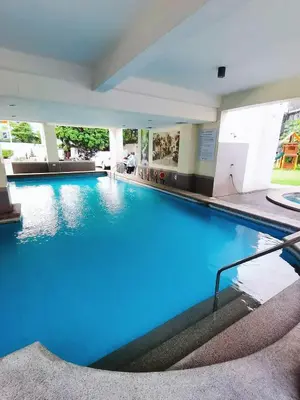 a large swimming pool with blue water in a building at Paradise Realm Condotel in Manila
