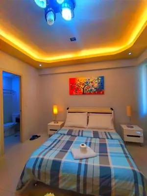 a bedroom with a bed with two tables and a painting at ONE PALM TREE VILLAS-Hyuna Place, Acros NAIA T3 in Manila