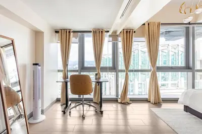 a bedroom with a desk and a bed and windows at Executive 1 Bedroom with Pool Sauna Gym and More in Manila