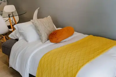 a bed with a yellow blanket and pillows on it at The Oasis 1 BR with Pool Sauna Gym and More in Manila