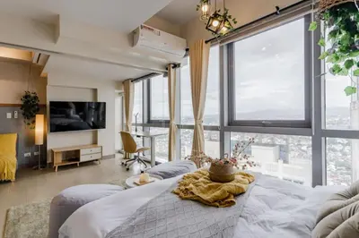a bedroom with a bed and large windows at The Oasis 1 BR with Pool Sauna Gym and More in Manila