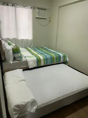 two beds in a room with a window at Eves Urban Haven in Manila