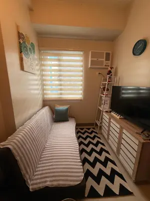 a small room with a couch in front of a television at Urban Oasis 2BR Condo with Multiple Pools at SMDC Charm Residences in Manila