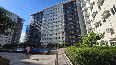a person standing in front of two tall buildings at Urban Oasis 2BR Condo with Multiple Pools at SMDC Charm Residences in Manila