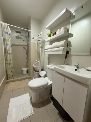 a white bathroom with a toilet and a sink at Urban Oasis 2BR Condo with Multiple Pools at SMDC Charm Residences in Manila