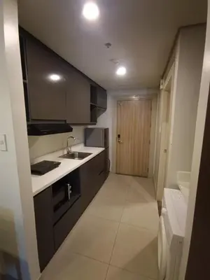 a kitchen with black cabinets and a sink and a door at GBA Condotel at Bonifacio Civic Center Tower in Manila