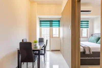 a dining room with a table and chairs and a bed at The Prestige Bayview with Balcony in Manila