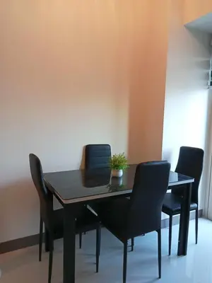 a dining room table with black chairs and a plant on it at The Prestige Bayview with Balcony in Manila