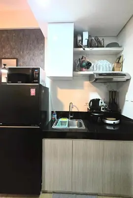 a kitchen with a sink and a black refrigerator at SW Staycation Sam Suite SMDC Hope Residences Beside SM City in Trece Martires