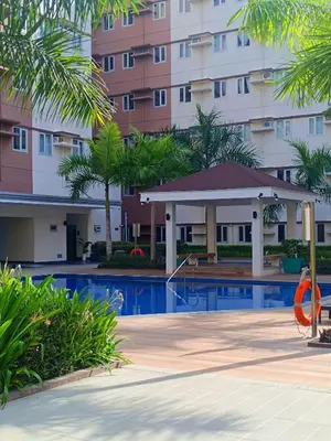 a swimming pool with a gazebo in front of a building at SW Staycation Sam Suite SMDC Hope Residences Beside SM City in Trece Martires