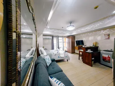 a bedroom with a couch and a bed in a room at COZI Venice Luxury Residences Alessandro BGC w Pool Gym in Manila