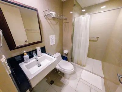 a bathroom with a sink and a toilet and a shower at COZI Venice Luxury Residences Alessandro BGC w Pool Gym in Manila