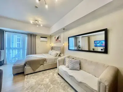 a living room with a couch and a large mirror at Condo Hotel type luxury Big Studio in Mckinley Hill taguig in Manila