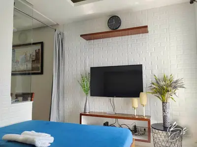 a bedroom with a blue bed and a tv on a wall at Birch Tower by Bright Space Manila in Manila