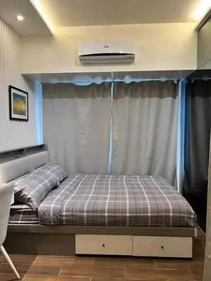 a bedroom with a bed with a curtain and a air conditioner at AM Condotel at Air Residences in Manila