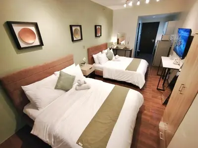 a hotel room with two beds and a bathroom at Air Residences-The House of Five 2Queen Bed in Manila