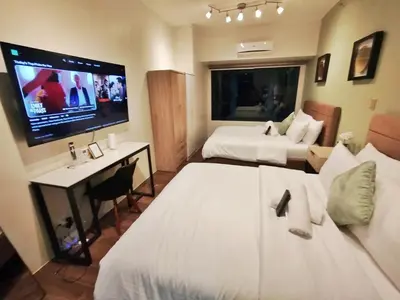 a hotel room with two beds and a flat screen tv at Air Residences-The House of Five 2Queen Bed in Manila