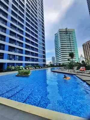 a large swimming pool in a city with tall buildings at Air Residences-The House of Five 2Queen Bed in Manila