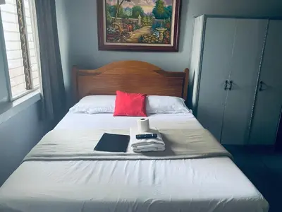 a bed with a red pillow and a book on it at Slouch Hat Hotel and Restaurant in Manila