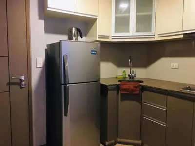 a kitchen with a stainless steel refrigerator and cabinets at Two Palm Tree Condotel in Manila
