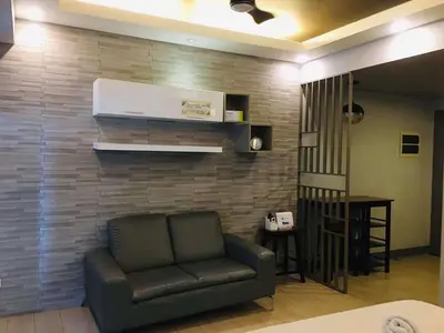 a living room with a couch and a brick wall at Two Palm Tree Condotel in Manila