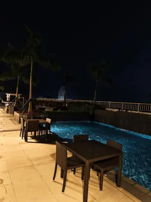 a table and chairs next to a swimming pool at night at Cozy Easy Escape in Manila