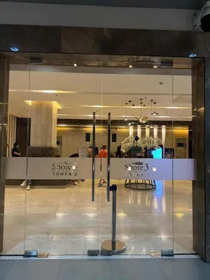 a glass door in a building with a person in the background at Staycation At Shore by LAYANDY in Manila