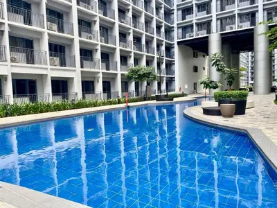 a large blue swimming pool in front of a building at Hotel-Like Staycation1 MOA Pasay in Manila
