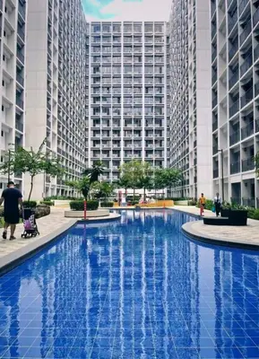 a large blue pool with tall buildings in the background at Hotel-Like Staycation1 MOA Pasay in Manila