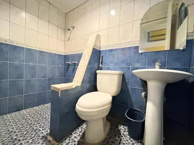 a blue tiled bathroom with a toilet and a sink at Town and Country Reposo in Manila